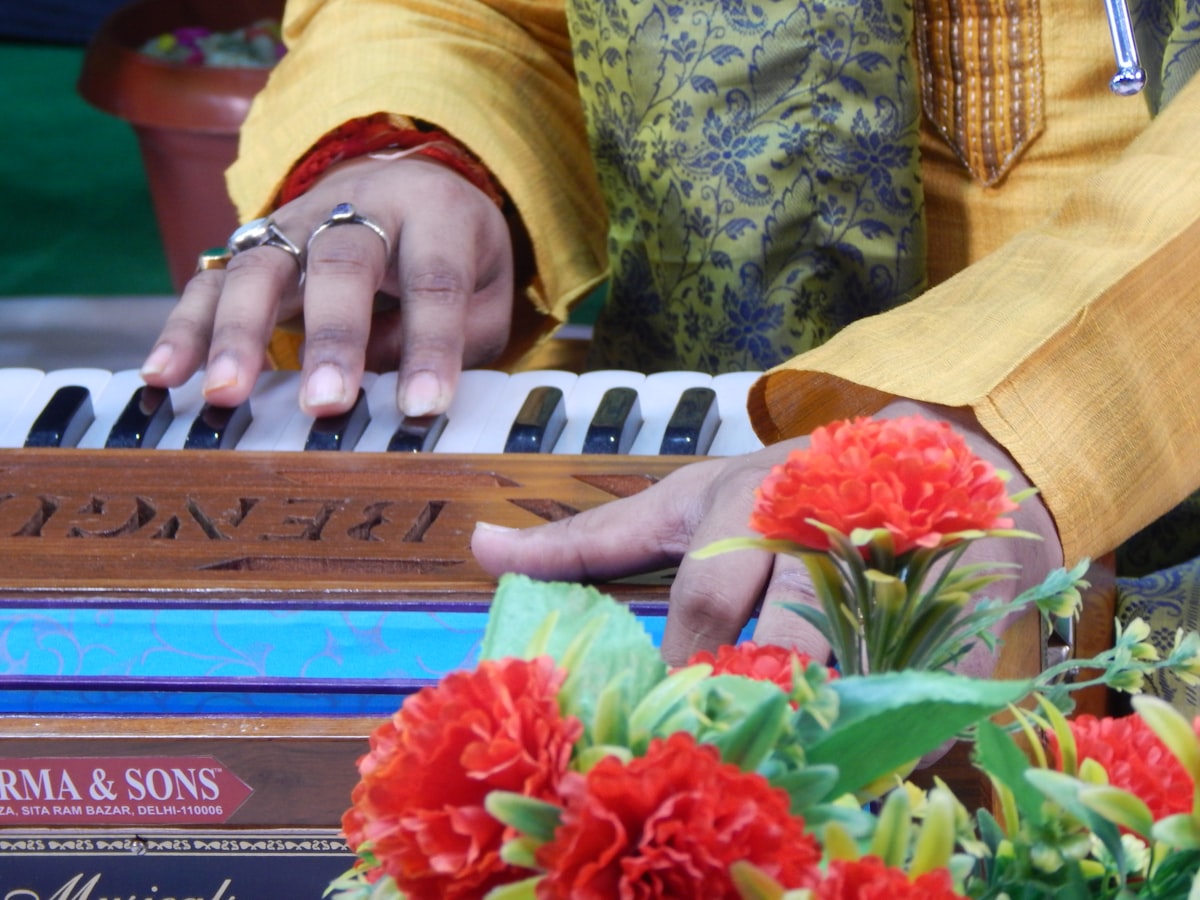 Hands playing a harmonium beside marigold flowers